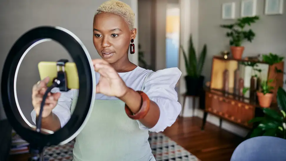 A person recording a video with a ring light and a smartphone.