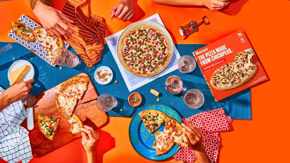 A top-down photo of people reaching for slices of pizza.