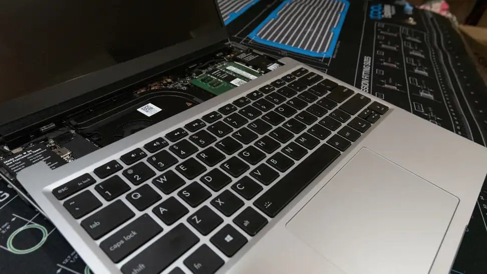 A laptop keyboard lays atop the main board, detached from its body