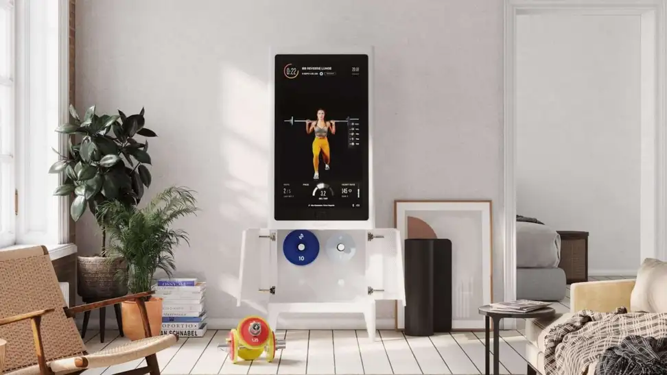 The Tempo Studio set up in a living room with dumbbells on the floor.
