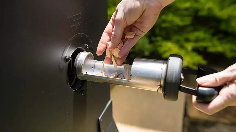 Girl putting wood chips into an electric smoker.