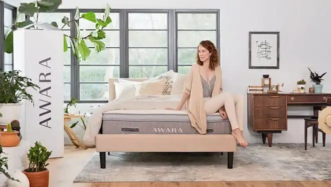 Person sitting on top of Awara mattress in bedroom.