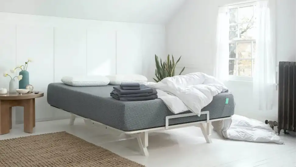 Mattress with sheets and blankets in bed frame in bedroom.