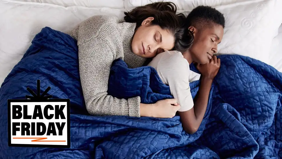 Two people sleeping peacefully in bed under big blue blanket.