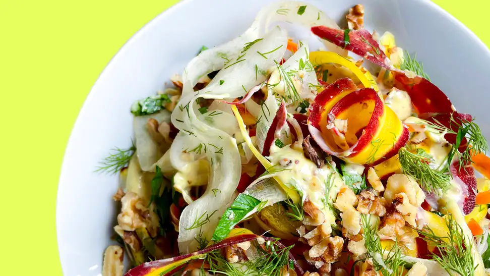 A bowl filled with carrot, herb, and dijonnaise salad.