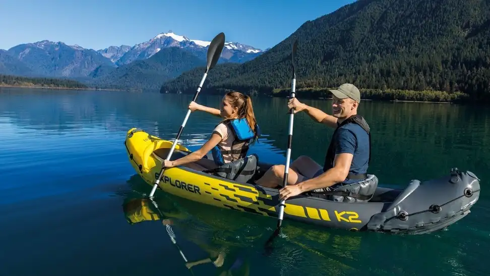 Photo of two people paddling a yellow Intex Explorer inflatable kayak on a body of water.