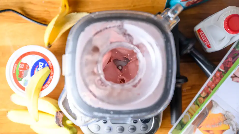 A blender viewed from above mixing a pink smoothie
