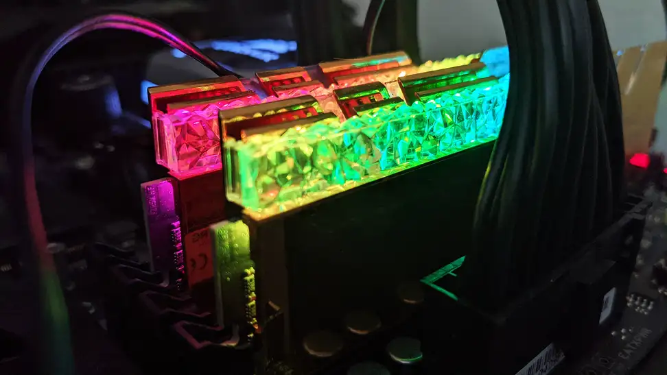 A close up of computer RAM attached to a motherboard and glowing different colors