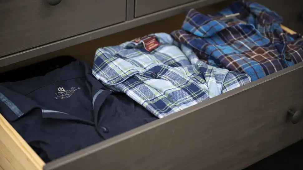 Set of men's pajamas inside of a dresser drawer.