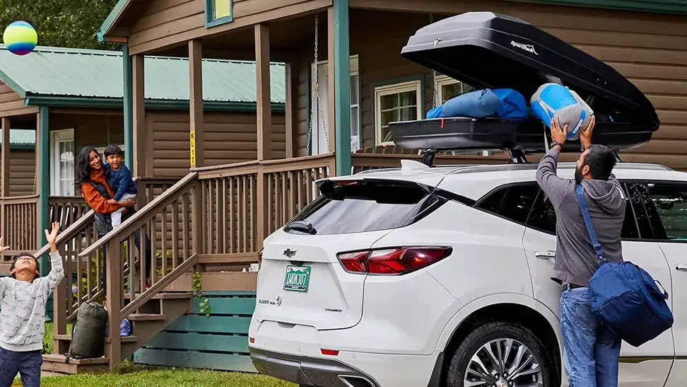 A family packs their camping gear into a cargo box for a weekend trip.
