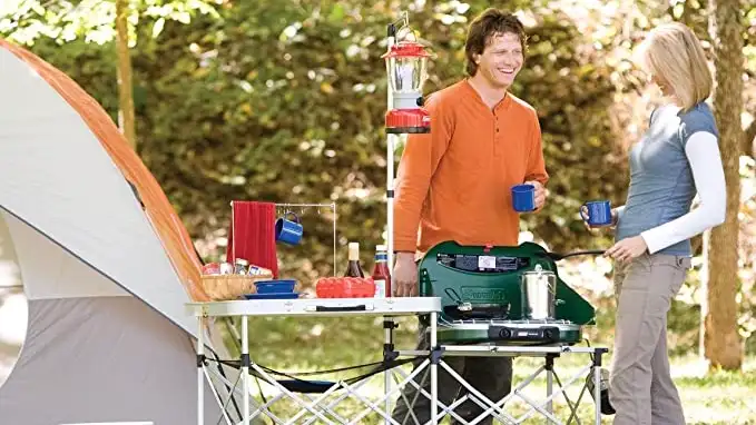 Two people using the Coleman Pack-Away Portable Kitchen outside