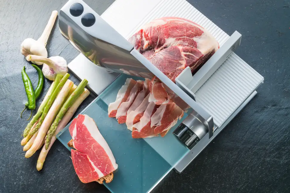 Meat being cut using a metal slicer.