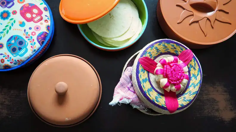 Five different tortilla presses sitting on a wooden background, shot from above.