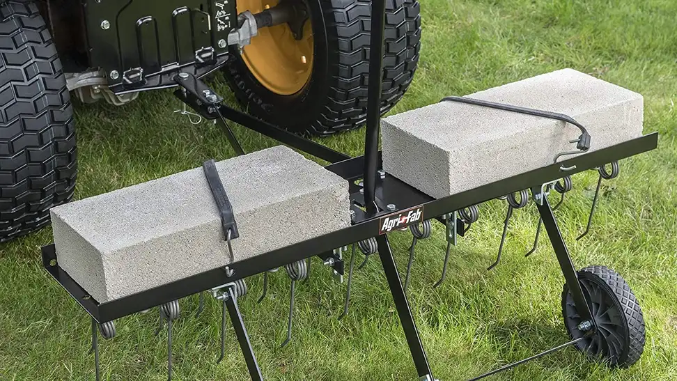 A homeowner working on their lawn with a lawn dethatcher.