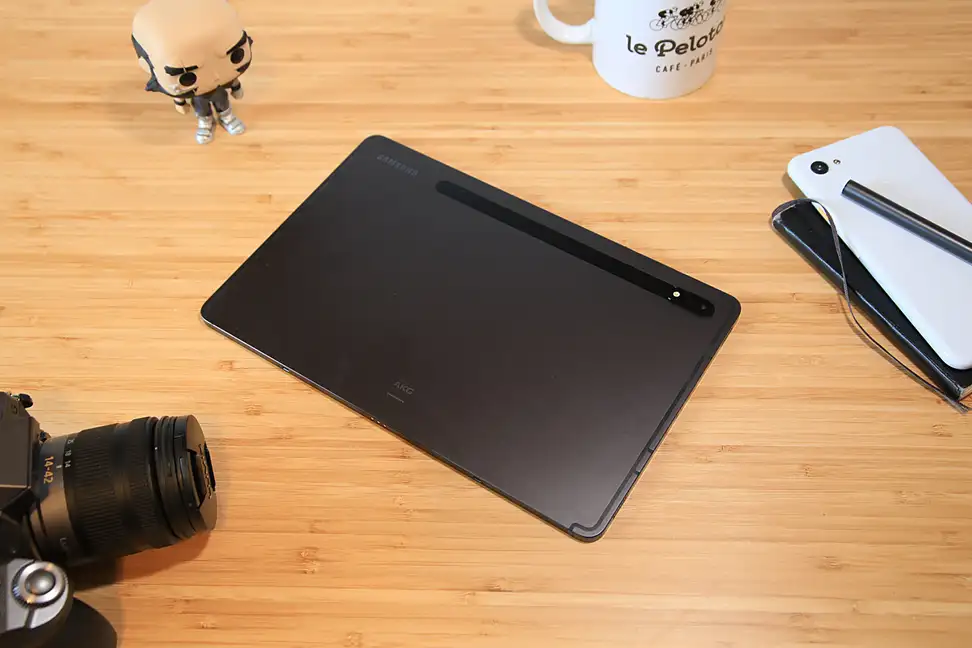 A flat black computing device on top of a light brown wooden surface