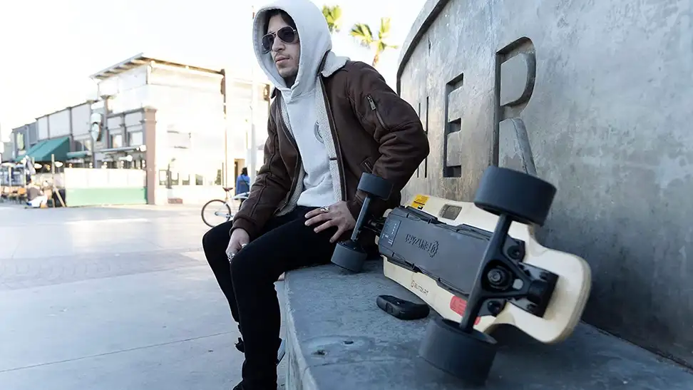 A longboard rider taking a quick break from riding his electric longboard.
