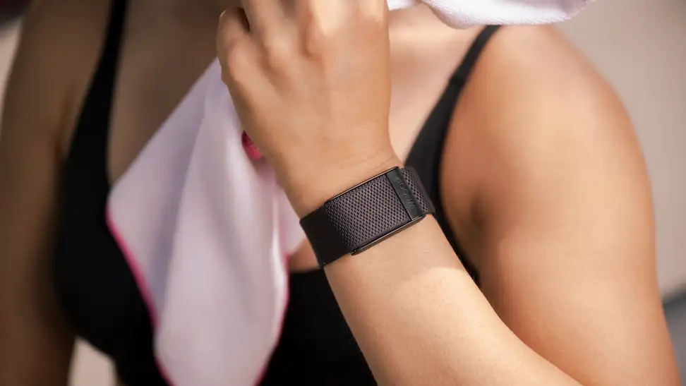 Person wearing Whoop 4.0 fitness tracker while working out with towel over shoulder.