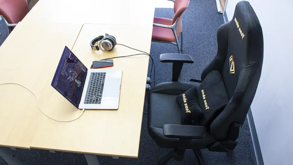 The AndaSeat Phantom 3 gaming chair placed in front of an office desk with a laptop and a pair of headphones.
