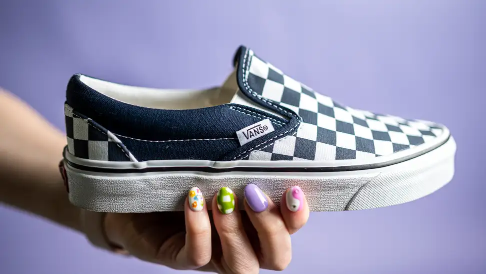 Close-up on a hand holding the Vans Checkboard slip-on.