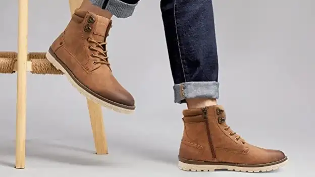 A person modeling a pair of tan motorcycle boots.