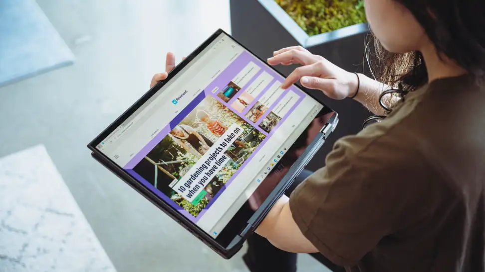 Person holds the laptop in their hands horizontally like a tablet