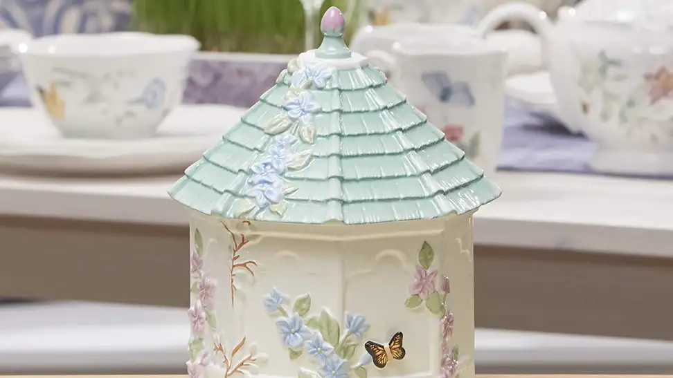 A beautiful meadow-styled cookie jar on a dining room table.