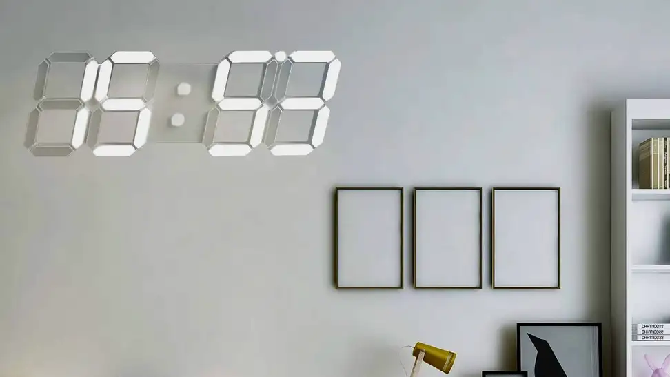 A white Wise Tiger digital wall clock hangs on the wall above a desk.