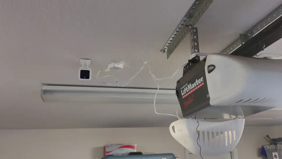A security camera hangs next to a garage door opener