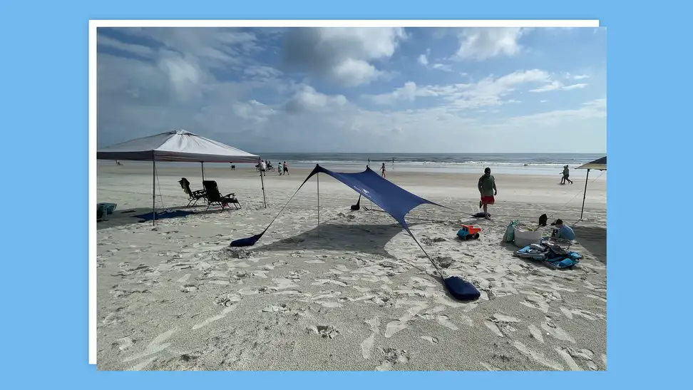 Beach tent propped up in sand outdoors.