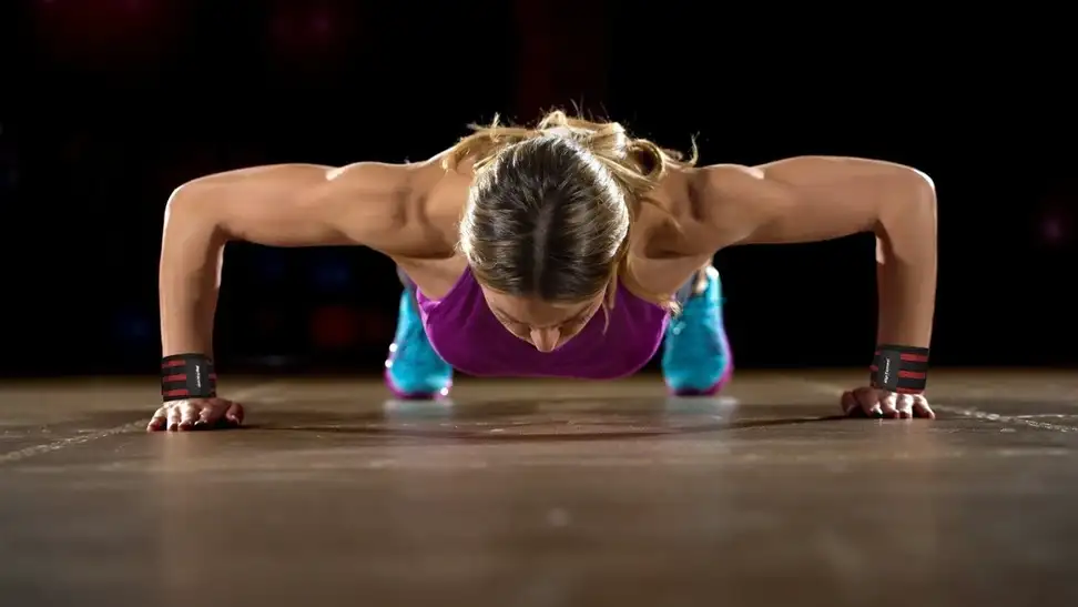 A bodybuilder using her wrist wraps during her workout.