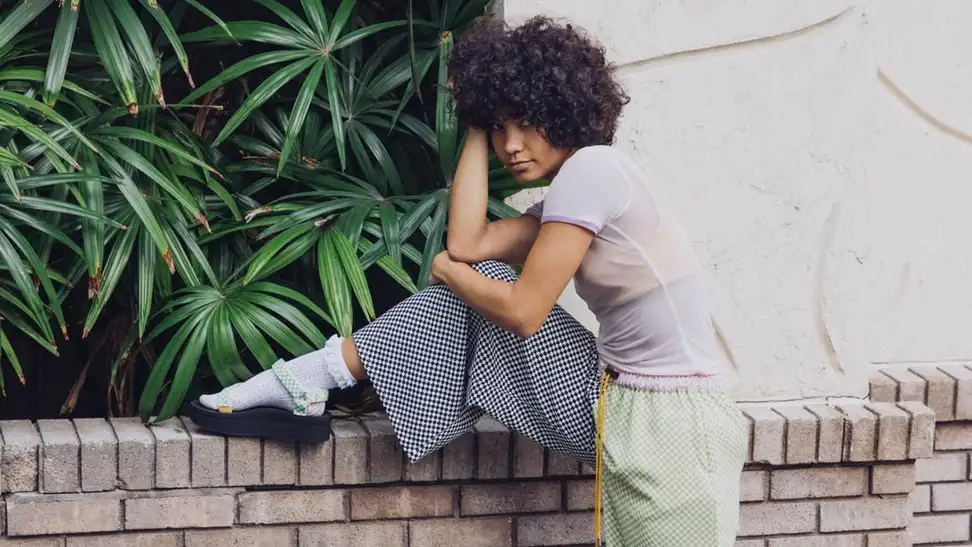A young model poses on a brick wall to show off their platform shoes.