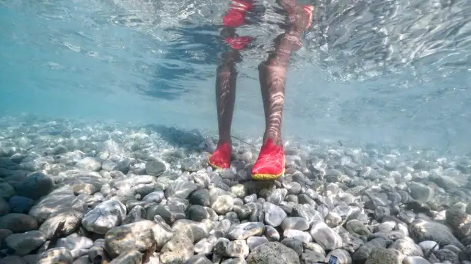 person wearing water shoes shown underwater