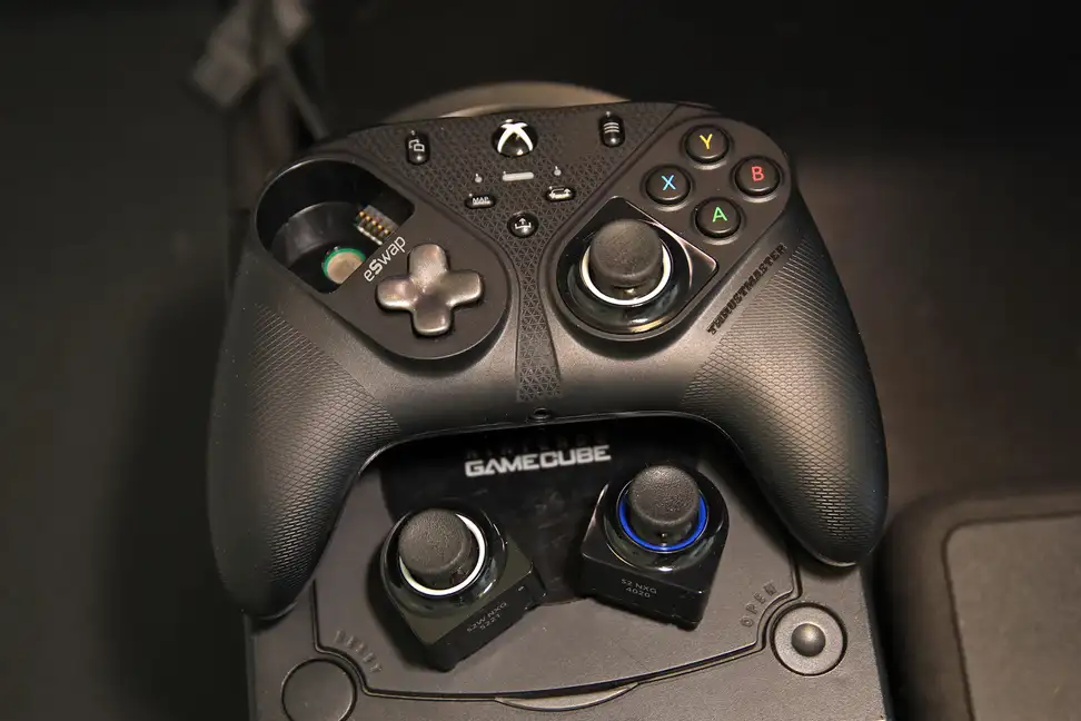 The Thrustmaster eSwap S Pro controller sitting atop a Nintendo Gamecube with spare thumbsticks on display..