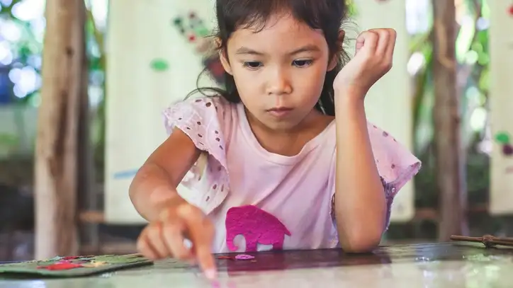 Child wearing pink shirt playing with stickers