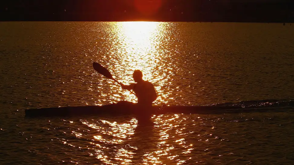 Kayak on a large sun-gilded lake at twilight.