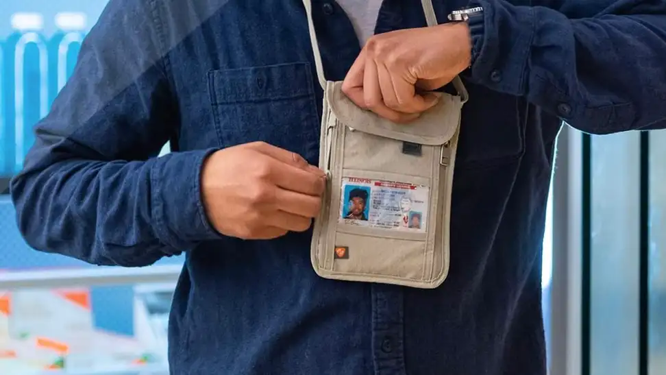 A person getting cash out of their travel wallet at the airport.