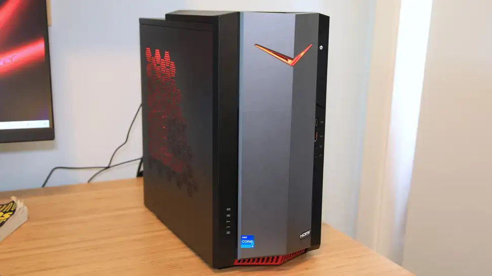 An Acer Nitro 50 desktop computer tower (center) next to a computer monitor on a desk.
