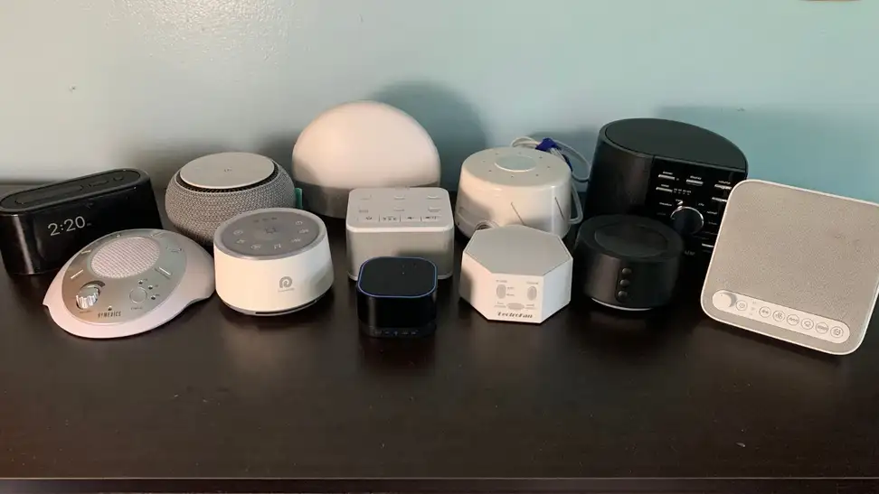 A collection of sound machines a grouped together on a dark brown surface