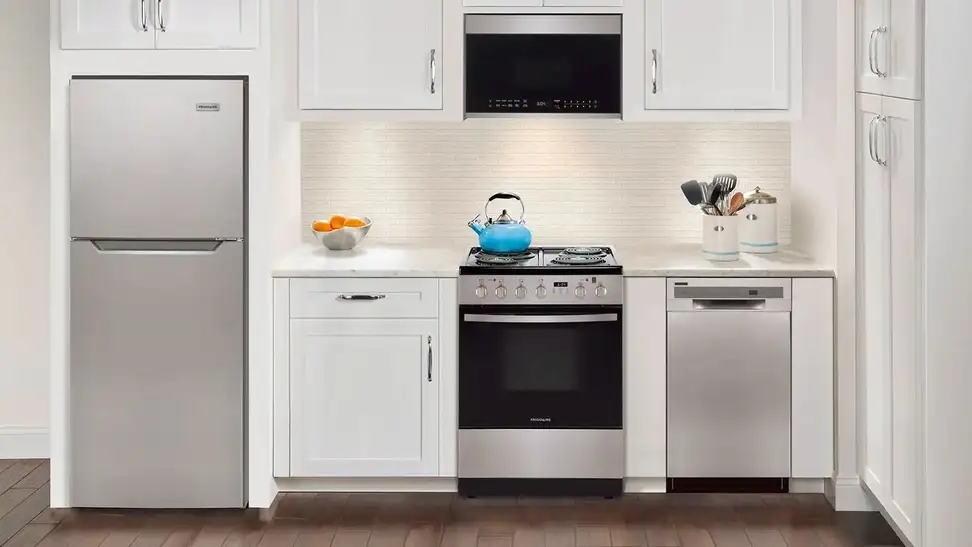 A small kitchen with a refrigerator, an oven range, utensils on the countertop, and so on.