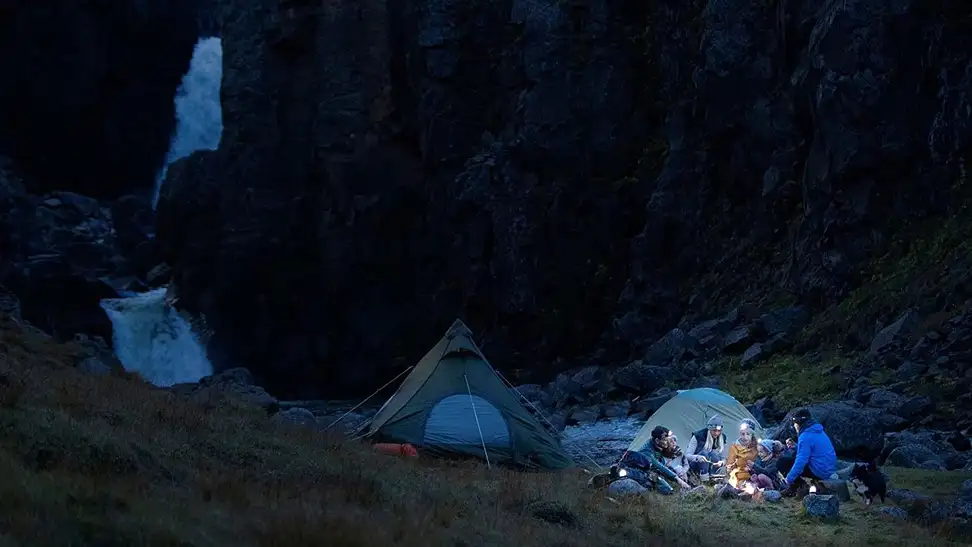 Campers hanging out and wearing headlamps.