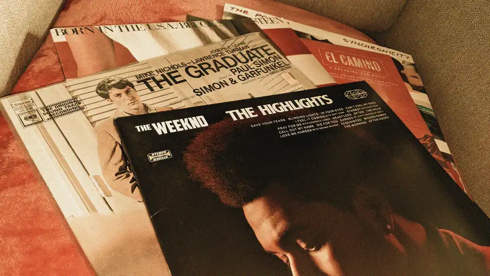 A handful of vinyl records: The Graduate by Simon and Garfunkel, The Highlights by the Weeknd, Born in the USA by Springsteen, the El Camino soundtrack, and Synchronicity by the Police.