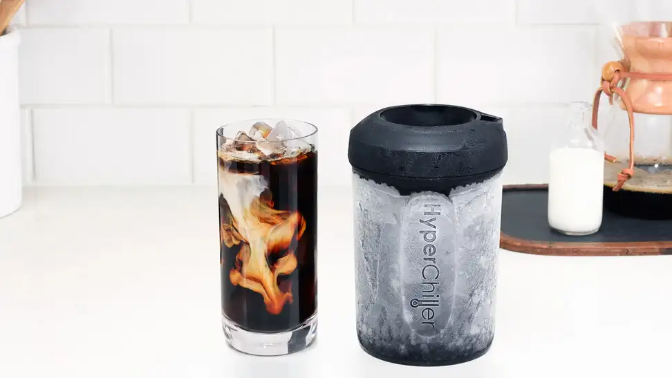 Cup of iced coffee with milk next to HyperChiller iced coffee maker on countertop