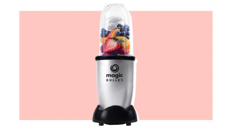Magic Bullet blender filled with fruit on a pink background