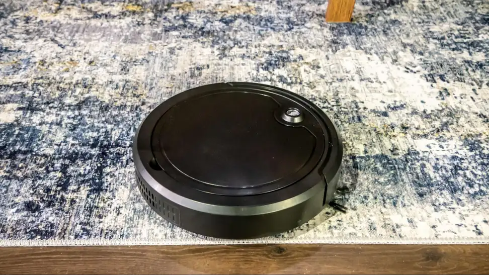 The Digital Essentials Robotic Vacuum Cleaner on a blue and white carpet.