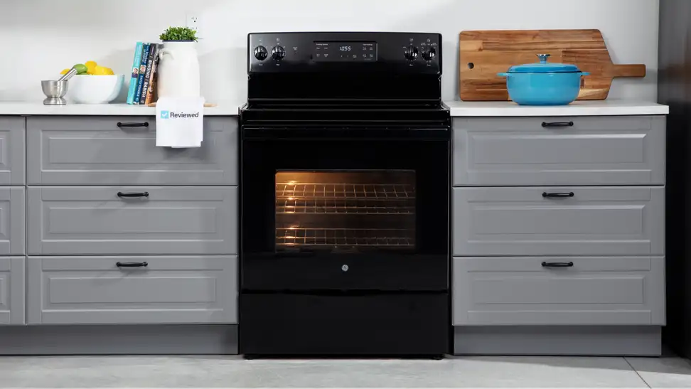 The GE JBS60DKBB electric range in black sits in a kitchen between grey cabinets.