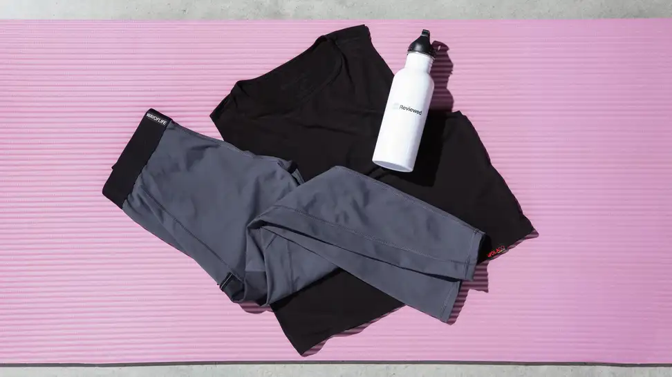 Wolaco grey legging and black tank top laid out with a white, Reviewed bottle.