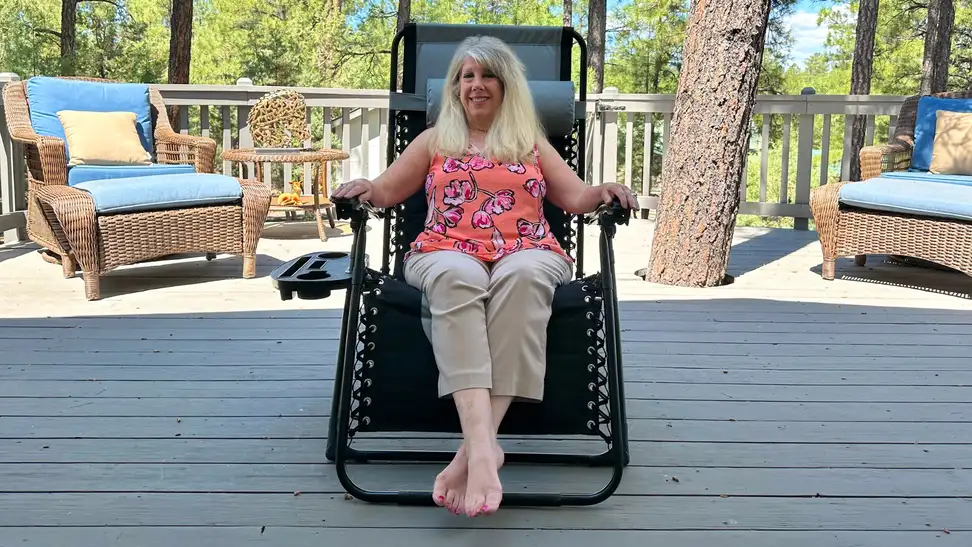 Person smiling while sitting in the Best Choice Products Oversized Padded Zero Gravity Chair outdoors on patio.