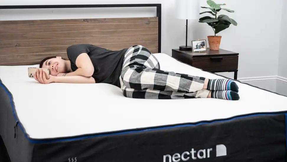 A woman reads her phone on the Nectar mattress
