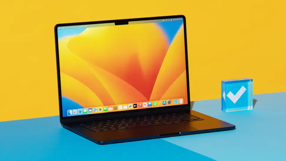 MacBook Air 15 M2 with display on sitting on top of blue surface next to acrylic paperweight.