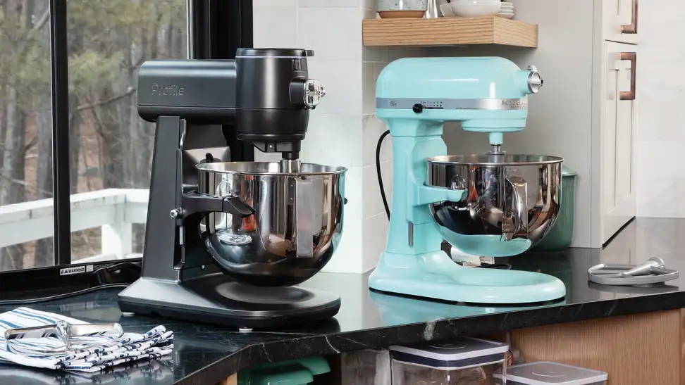 Black GE Profile and aqua KitchenAid stand mixer sit on a kitchen counter in front of a window.